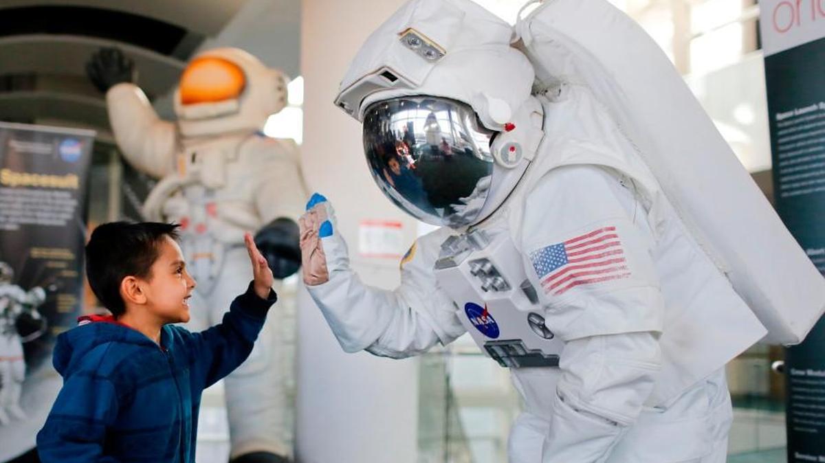 Carlos Chavez, 5, gives Dustin Hitt, dressed as a NASA astronaut, a high-five during Astronomy Days in 2015.
