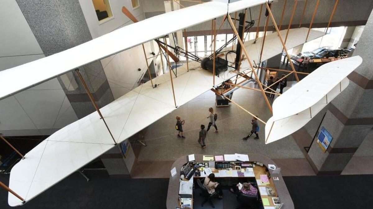 Visitors walk under the  reproduction of the 1903 Wright Flyer at the N.C. Museum of History in 2016.