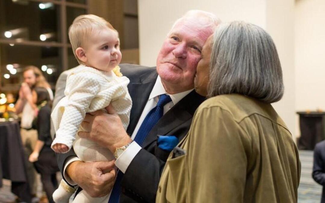 Roger Krupa, holds his 8-month-old granddaughter Maezy Lee Krupa while receiving a greeting from Sharon Banks during his retirement reception Monday, December 14, 2015 in Raleigh, N.C.