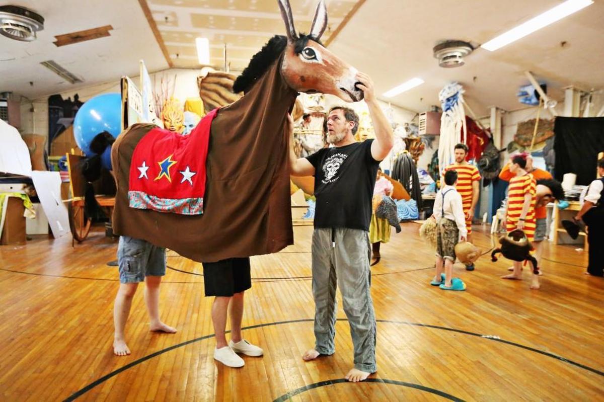 Donovan Zimmerman, right, looks over the mule costume worn by Kelly Washatka, left, and Jake Brower, right, during rehearsal Thursday evening, July 20, 2017, in Saxapahaw for Paperhand Puppet Intervention's upcoming production of “Of Wings and Feet.”