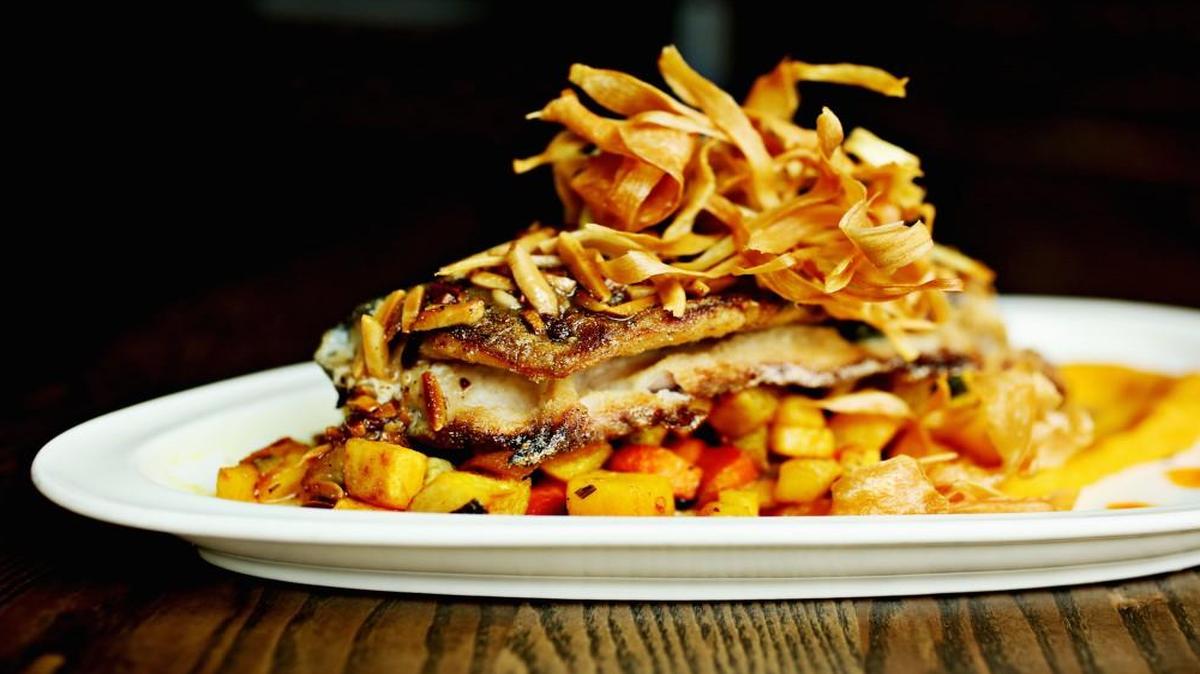 The pan-roasted North Carolina trout is served over butternut squash puree and roasted root vegetables, garnished with toasted almonds and microgreens at H Street Kitchen in Raleigh.