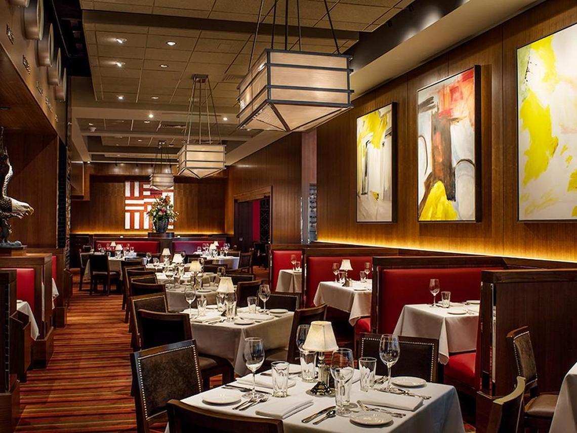 The dining room at The Capital Grille is designed to set an opulent mood: deep leather banquettes, shaded brass candlestick lamps on tables draped in white linens, wood-paneled walls, floor carpeted in rich hues of russet and sepia.