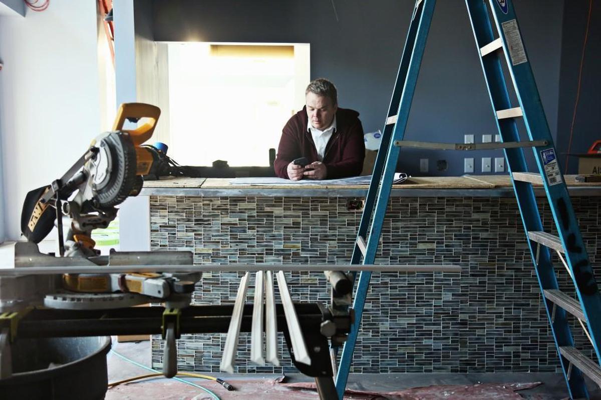 Chef Brendan Cox of Oakleaf looks over blueprints on the bar in the new restaurant space in Carrboro as construction work continues around him Tuesday, Feb. 6, 2018.