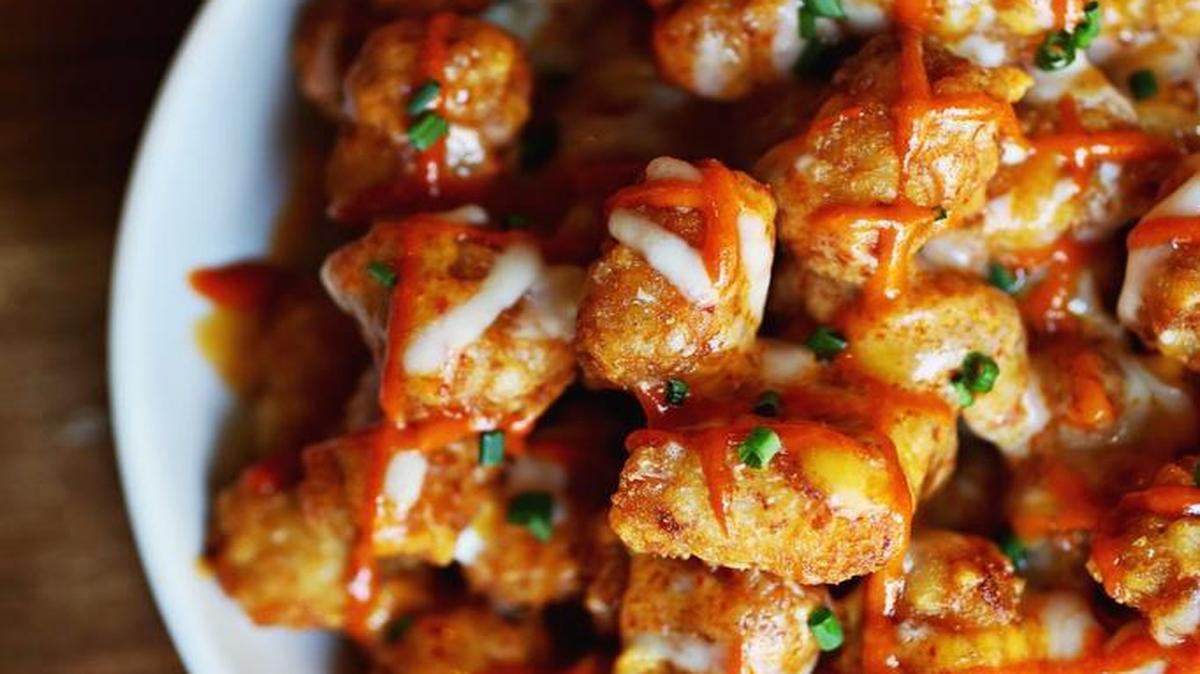 The Tochos at The District in Raleigh are tater tots tots topped with kimchi cheese sauce and sour cream.