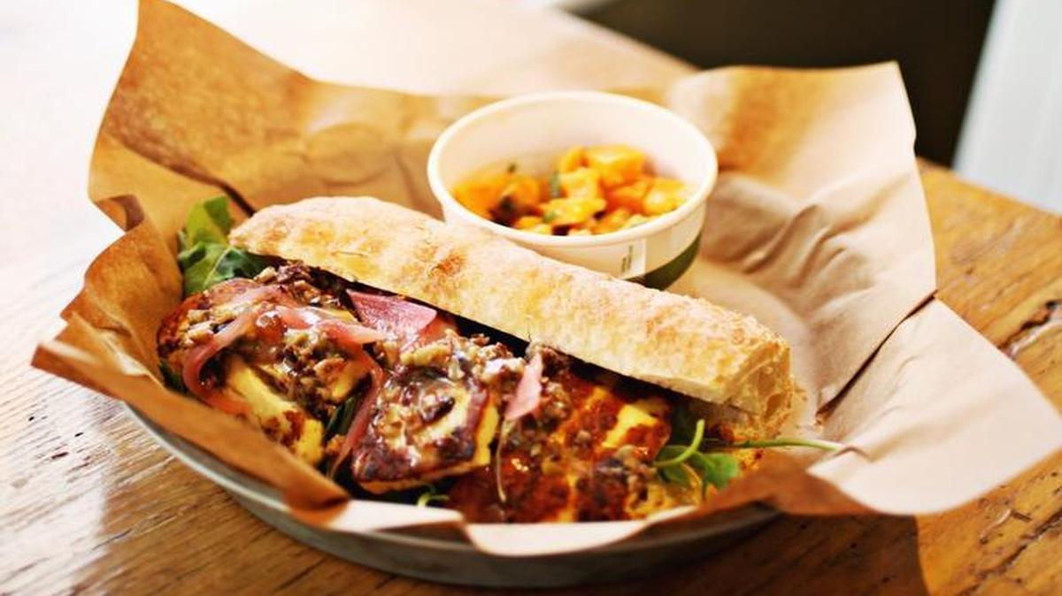 The Griddled Haloumi Cheese sandwich is made up of olive tapenade, pickled red onion, slow roasted tomato, lemon rosemary aioli and spicy mixed greens on a baguette at The Pharmacy Cafe in Raleigh. Here it is served with a side of sweet potato salad.