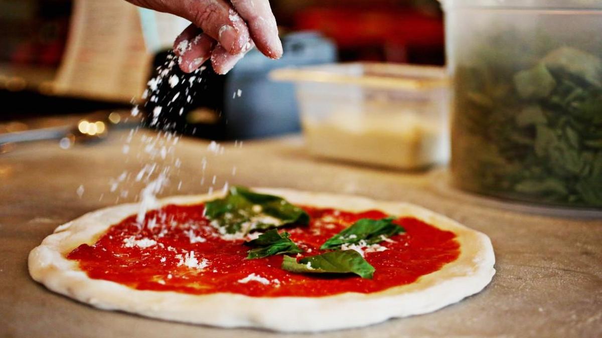 Chef Manuel Sarri Pellegrini sprinkles cheese on a pizza at Treforni in Durham on Tuesday, June 7, 2017.