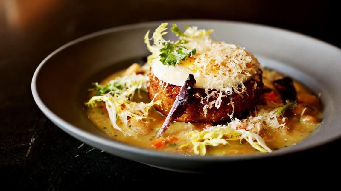 The crispy duck croquette is served over cannellini beans in a garlicky broth that’s evocative of a cassoulet, and topped with a poached duck egg at Crawford & Son in Raleigh .