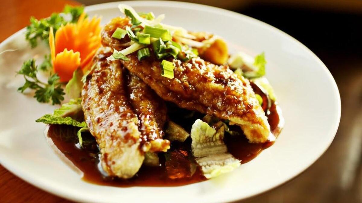 The Crispy Catfish is made up of fried catfish fillets served with ginger sauce on a bed of lettuce topped with fresh ginger and scallions at Thai Lotus in Cary.