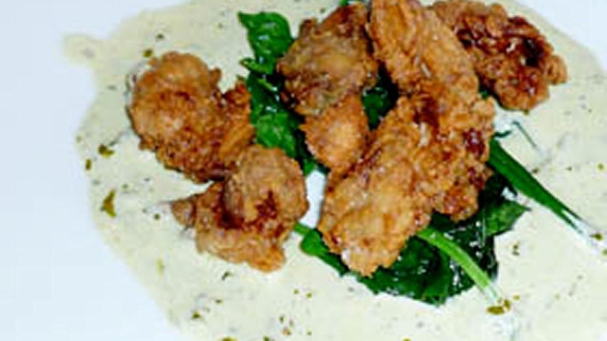 Fried oysters over wilted spinach with smoked mozzarella and pesto fondue is served at Chef & the Farmer in Kinston.