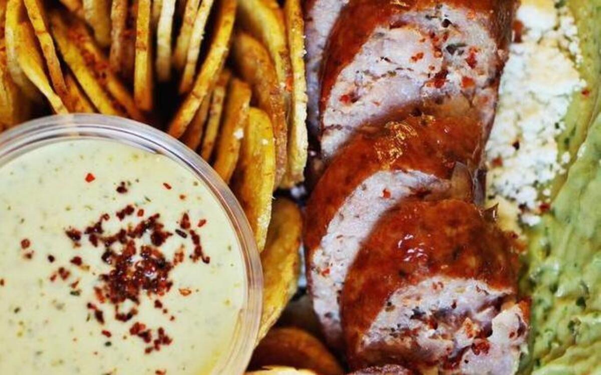 The Mestizo sandwich from the Route Bistro food truck features Argentinean pork sausage on a grill-pressed Mexican bolillo bun lined with guacamole, kraut and crumbled cotija cheese, served with plantain chips.