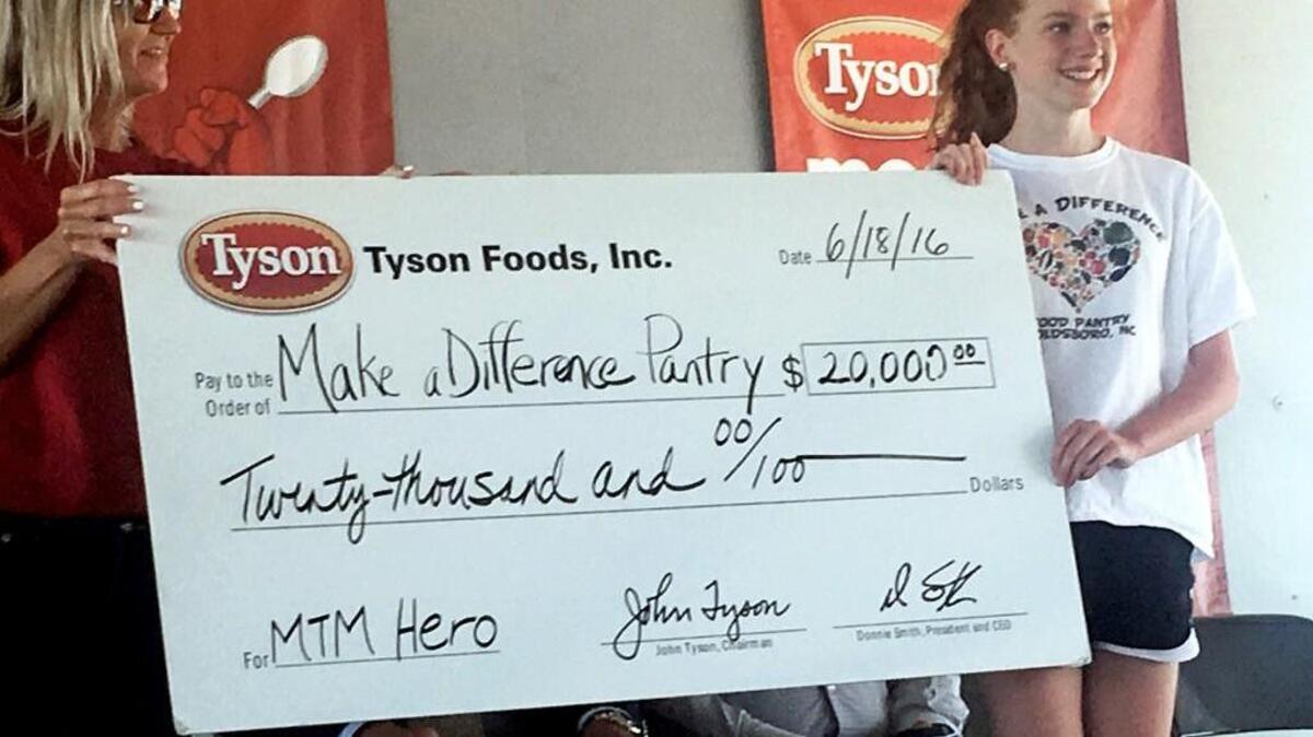 Annetta Tirey, left, director of corporate social responsibility for Tyson Foods, presents a $20,000 check to Kenzie Hinson, 12, founder of the Make A Difference Food Pantry in Goldsboro. The check was given in a surprise announcement Saturday, June 18, 2016.
