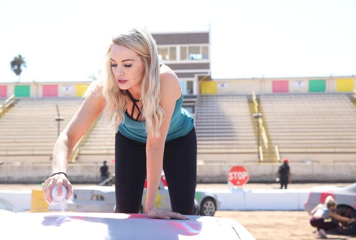 Jenna Cooper spray paints a car during a group date at a demolition derby on ABC’s “The Bachelor.”
