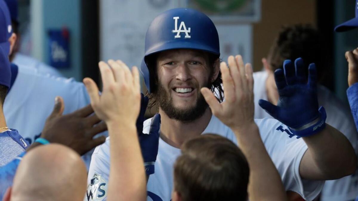 Los Angeles Dodgers pitcher Clayton Kershaw is greeted with high-fives in the dugout after a succesful third-inning sacrifice bunt against the Houston Astros in Game 1 of the World Series at Dodger Stadium in Los Angeles on Tuesday, Oct. 24, 2017. The Dodgers won, 3-1.