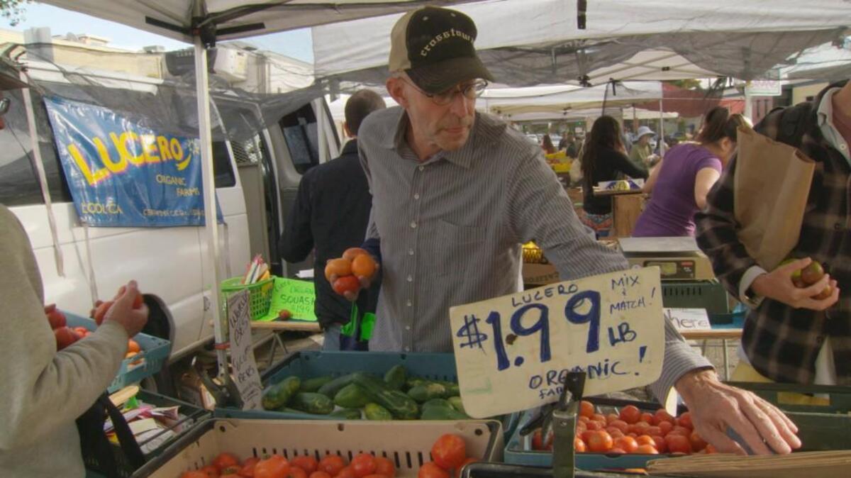 Michael Pollan shops for vegetables at a farmers market.