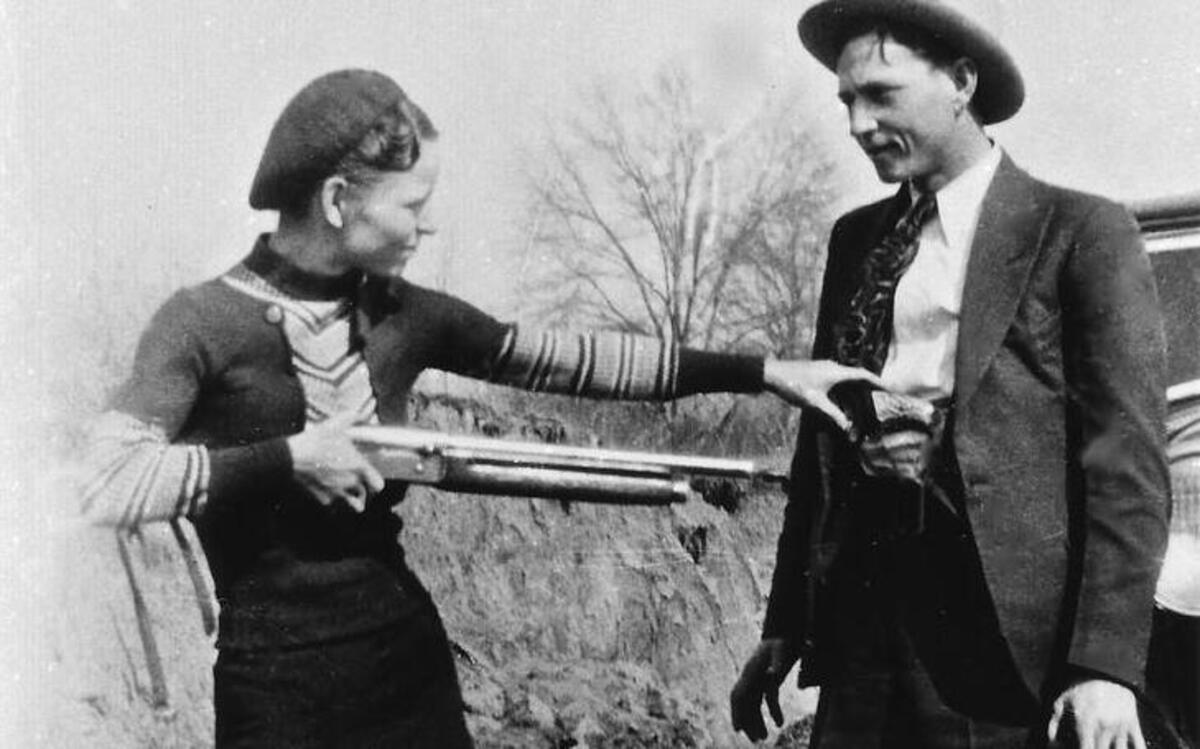 Bonnie Parker and Clyde Barrow, the most famous outlaw couple in U.S. history, posing together in front of car, 1933.