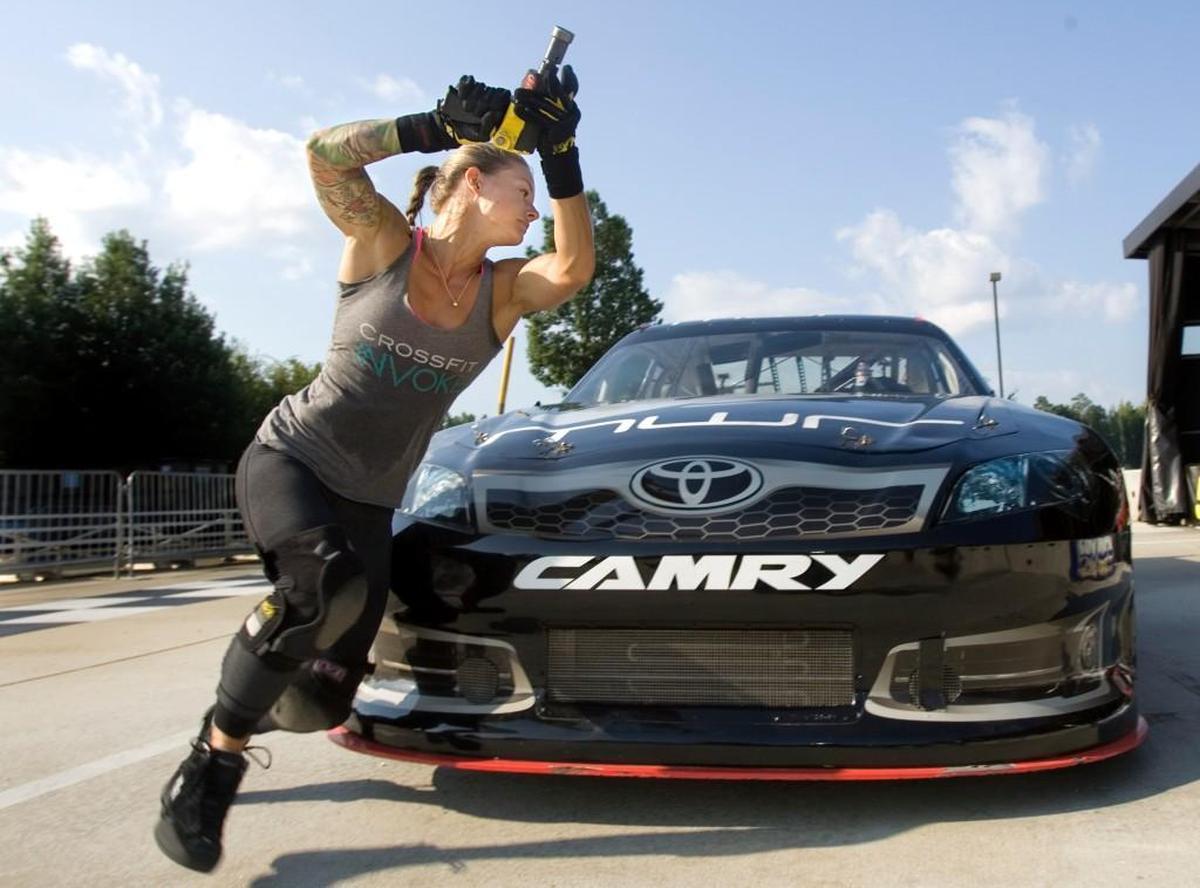 In the early days of her pit crew training in August 2012, and with no hose connected to her air gun, Christmas Abbott practices her technique and speed moving around the front end of a stock car.
