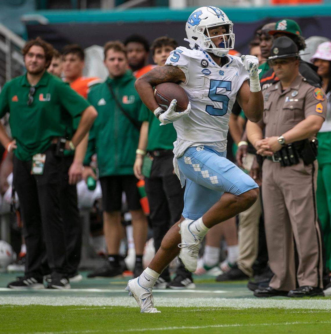 North Carolina J.J. Jones (5) races for a 74-yard touchdown in front of the Miami bench, on a pass from North Carolina quarterback Drake Maye (10) to take a 7-0 lead in the first quarter on Saturday, October 8, 2022 at Hard Rock Stadium in Miami Gardens, Florida.
