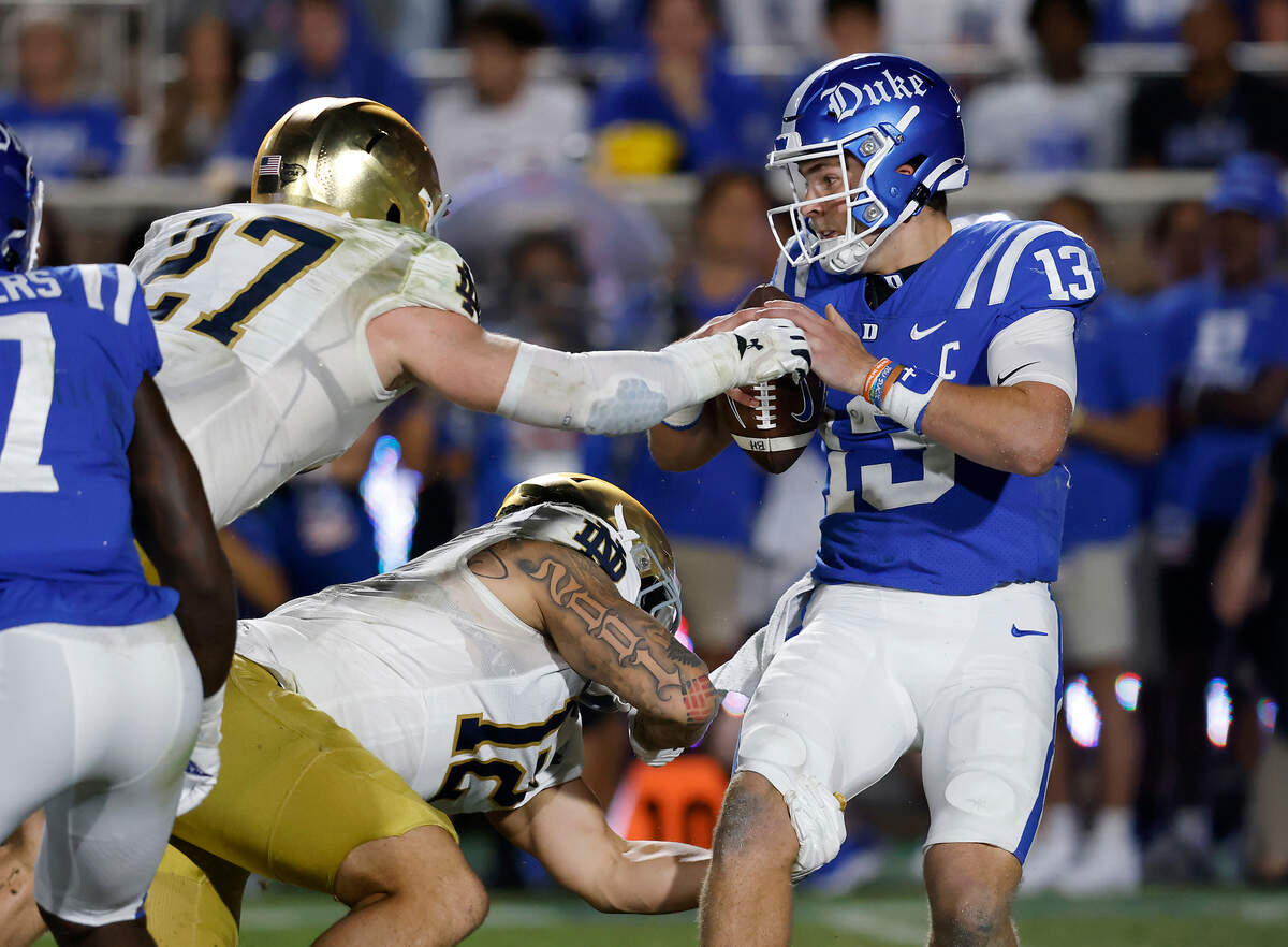 Duke’s Riley Leonard looks to pass under pressure from Notre Dame’s JD Bertrand and Jordan Botelho during the first half of the Blue Devils’ game at Wallace Wade Stadium on Saturday, Sept. 30, 2023, in Durham, N.C.
