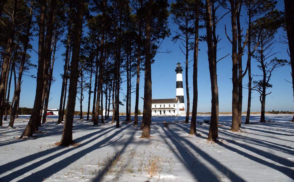 With fresh snow on the ground, The Bodie Island Lighthouse is framed by a thicket of pine trees, and their shadows cast by the afternoon sun after a winter storm dumped eight inches of snow on the Outer Banks in January 2003.