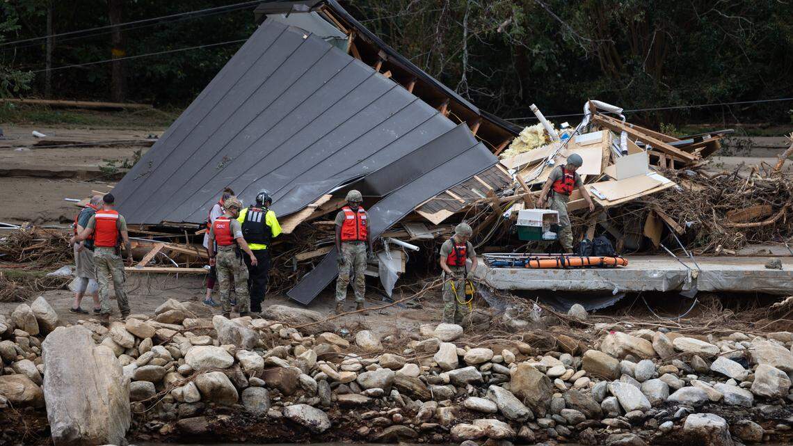 Two people and a dog are escorted to a rescue boat in Chimney Rock, N.C. on Sunday, September 29, 2024.