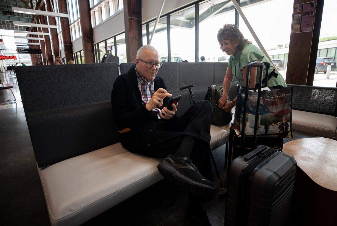 Paul and Carol Tompkins search for rental cars on their phone after an Amtrak train cancellation left them stranded at Union Station in Raleigh on Tuesday, July 11, 2023. Amtrak was forced to cancel northbound traffic after a train derailed in Washington, D.C., blocking the tracks. The Tompkins were headed from Charlotte, N.C. to Alexandria, V.A. to visit their son and daughter-in-law. “I’m just trying to keep my sense of humor,” Carol said. “We’re two old people who were looking forward to a calm, uneventful trip.”