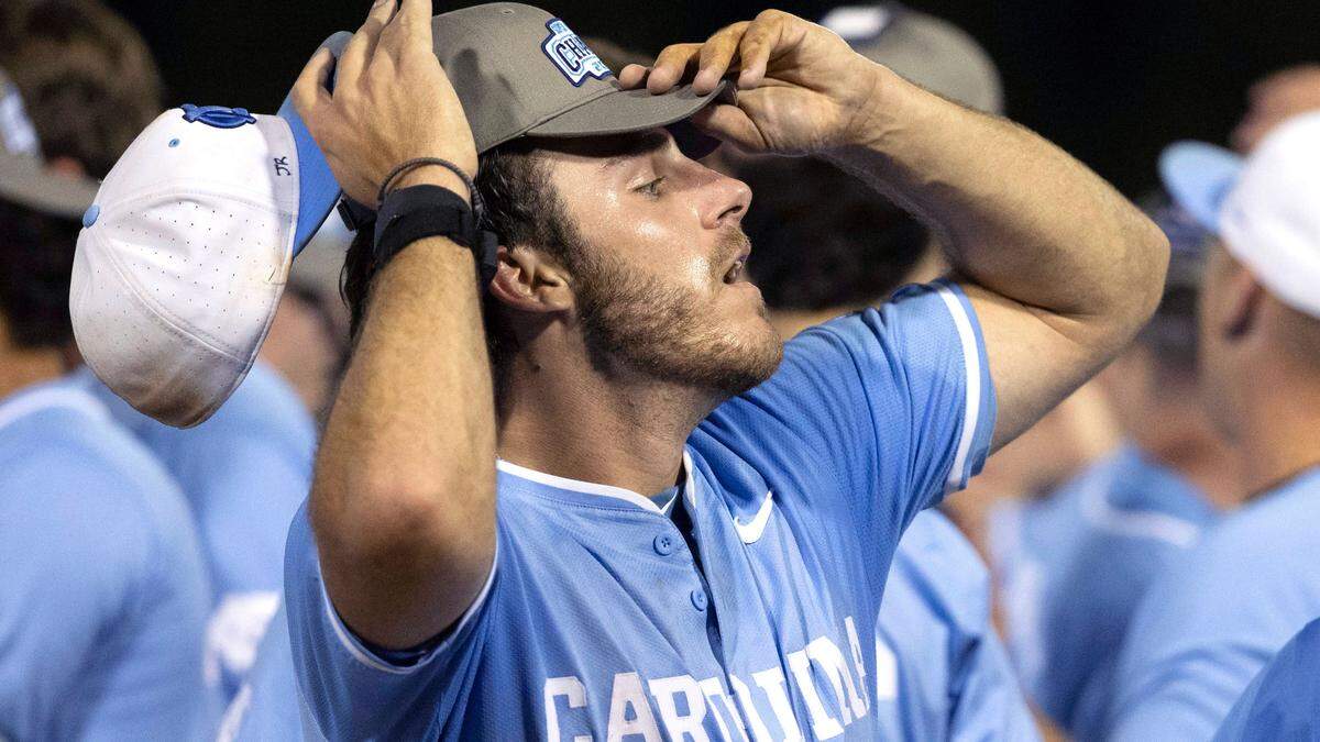 North Carolina pitcher Dalton Pence removes his game cap with the small initials ‘JR’ written above the bill, as he dons a 2024 Super Regional Championship cap following the Tar Heels’ victory over West Virginia on Saturday, June 8, 2024 at Boshamer Stadium in Chapel Hill, N.C. J.R. Anton became a friend of the Tar Heel baseball program in 2006 during the College World Series in Omaha. Upon his death last month, the players have all written J.R.’s initials on their game caps as a tribute to him.
