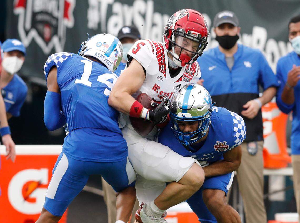 N.C. State wide receiver Thayer Thomas (5) makes the reception as Kentucky defensive back Carrington Valentine (14) and safety Vito Tisdale (7) hit Thomas during the second half of Kentucky’s 23-21 victory over N.C. State in the Gator Bowl at TIAA Bank Field in Jacksonville, Fla., Saturday, January 2, 2021.