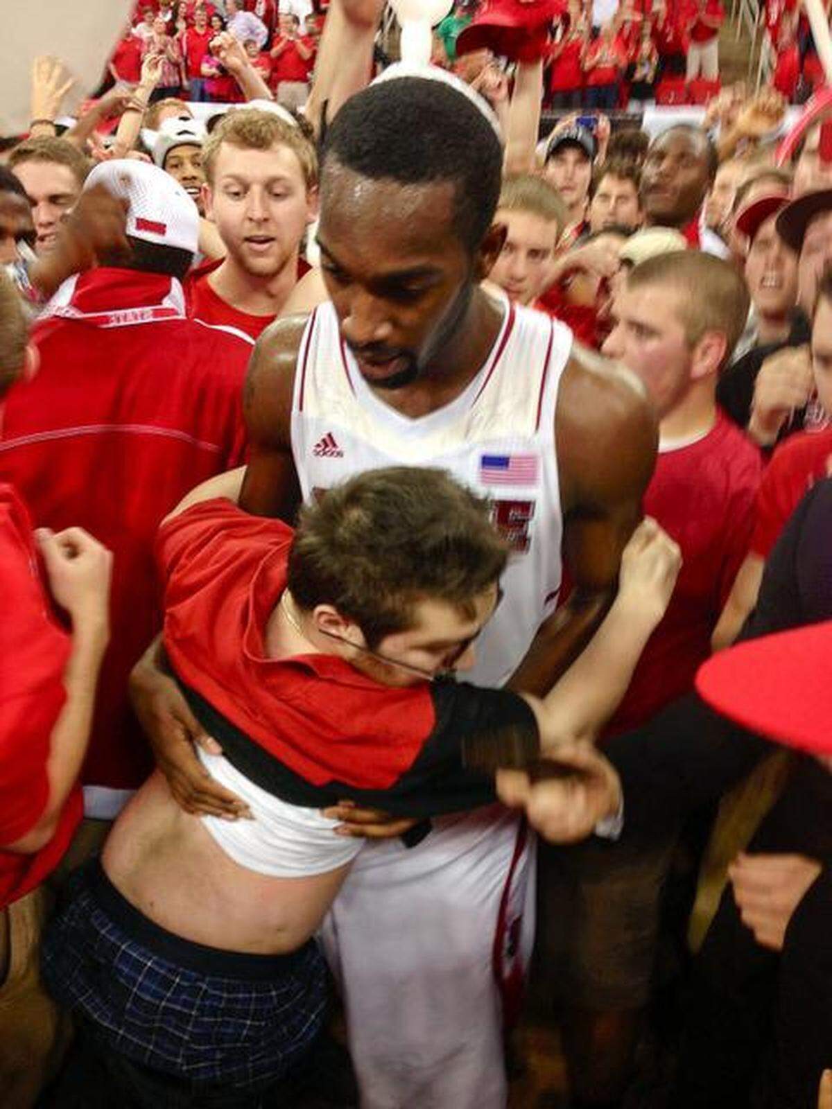 NC State’s CJ Leslie helps Will Privette who had fallen from his wheelchair after fans rushed the court at the conclusion of the Wolfpack’s upset win over Duke at the PNC Arena.