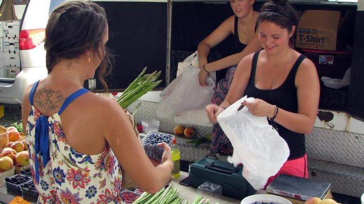 Anna Sullivan, right, helps a customer at the Durham Farmer’s Market on Wednesday, Aug. 6, 2014. The women work for Lyon Farms in Creedmoor, which is a participant in the farmer’s market Double Bucks program benefiting low-income residents.