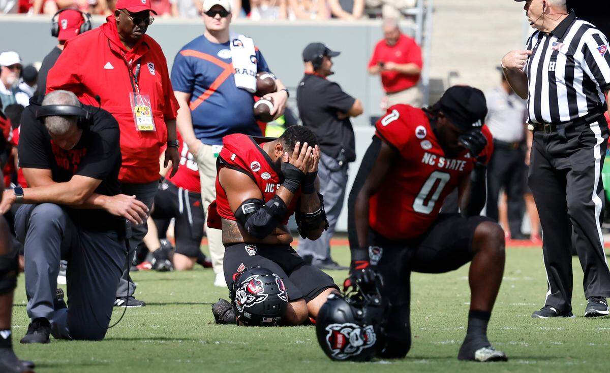 N.C. State defensive end Davin Vann (1) reacts as quarterback Grayson McCall (2) is attended to after he was injured during the first half of N.C. State’s game against Wake Forest at Carter-Finley Stadium in Raleigh, N.C., Saturday, Oct. 5, 2024.