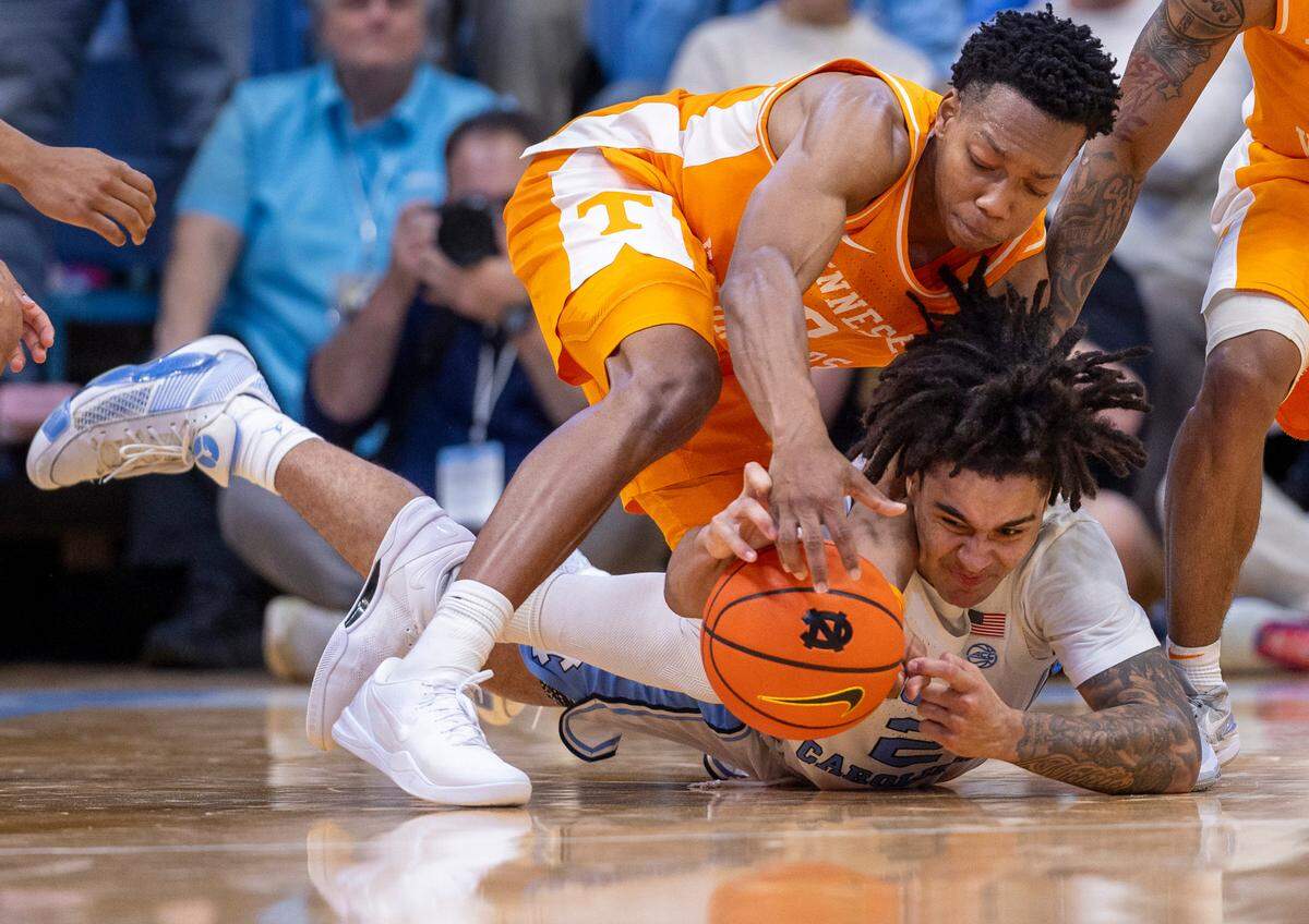 North Carolina’s Elliot Cadeau (2) and Tennessee’s Jonas Aidoo (0) dive to collect a loose ball in the final seconds of play on Wednesday, November 29, 2023 at the Smith Center in. Chapel Hill, N.C.