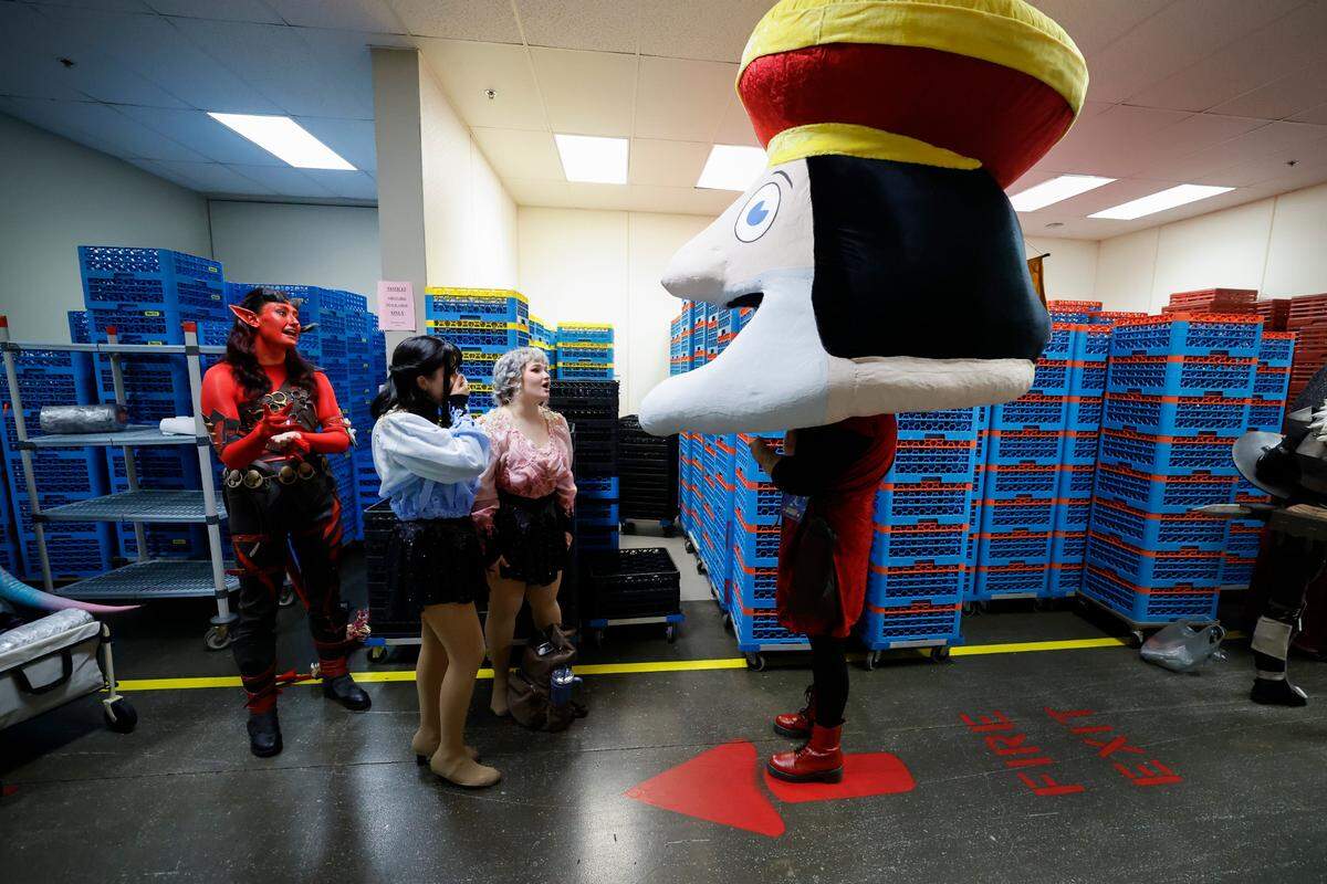 Kaitlin Holshouser, dressed as the Duloc mascot from Shrek wearing a Lord Farquaad head, waits backstage with other contestants before the costume competition at GalaxyCon Raleigh at the Raleigh Convention Center Saturday, July 27, 2024.