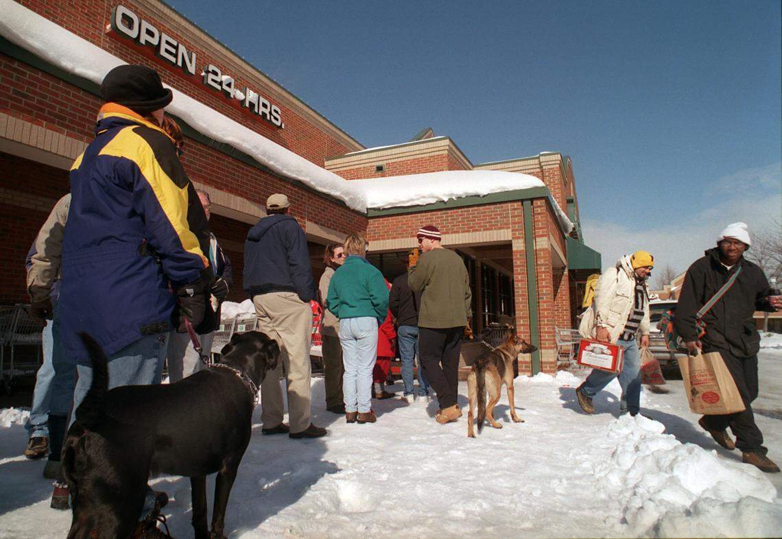 Following the 2000 storm, Amy Fuson, left, with her dog, Bob, wait on line with her mother, Sue, and dozens of others for thier opportunity to shop at the Harris Teeter at Olde Raleigh Village, as Roy Dockery, far right, and his step father, Jeffery Clark, begin their 20 minute walk home with their groceries.