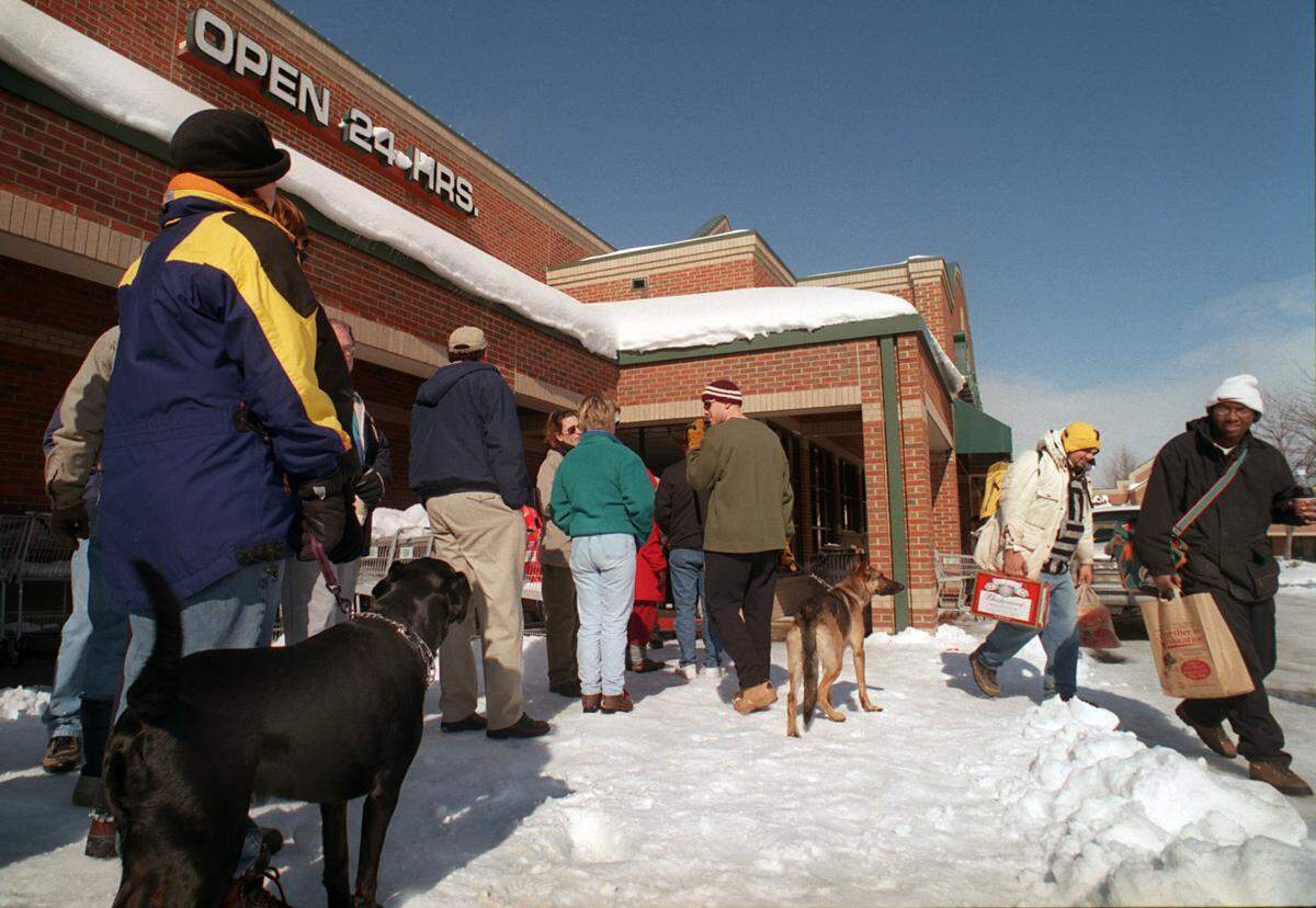 Following the 2000 storm, Amy Fuson, left, with her dog, Bob, wait on line with her mother, Sue, and dozens of others for thier opportunity to shop at the Harris Teeter at Olde Raleigh Village, as Roy Dockery, far right, and his step father, Jeffery Clark, begin their 20 minute walk home with their groceries.