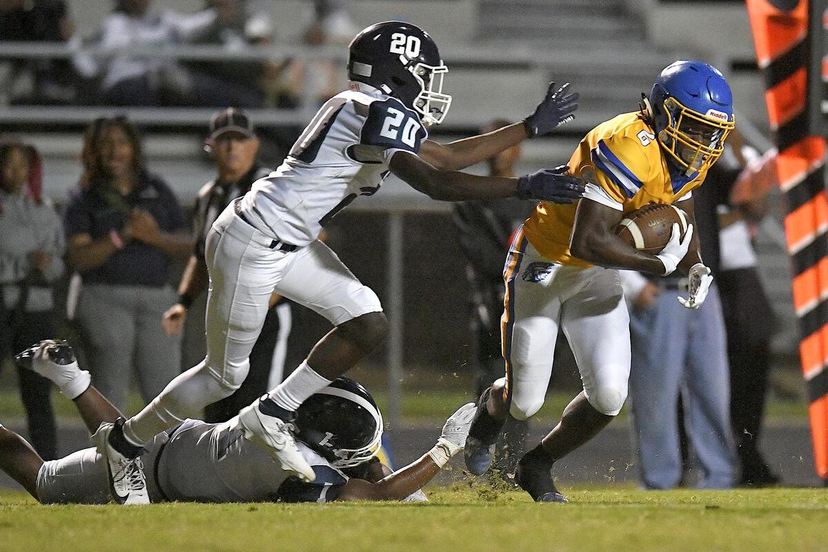 GArner’s Isaiah Dawson (6) runs for yardage ahead of Southeast Raleigh’s Alex Wiliams (1) and Zykir Gbor (20) during the first half. The Garner Trojans and the Southeast Raleigh Bulldogs met in a conference football game in Garner, N.C, on October 6, 2023