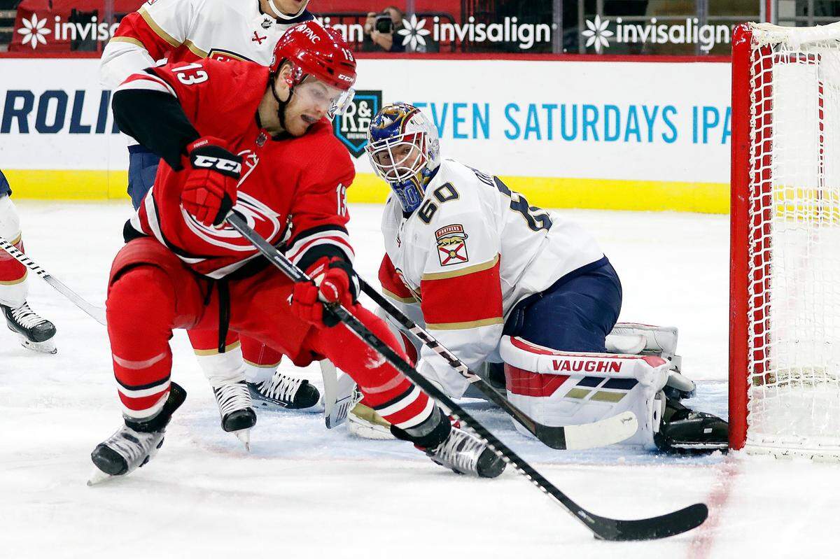Carolina Hurricanes’ Warren Foegele (13) tries to control the puck and shoot it at Florida Panthers’ goaltender Chris Driedger (60) during the second period of an NHL hockey game in Raleigh, N.C., Sunday, March 7, 2021. (AP Photo/Karl B DeBlaker)