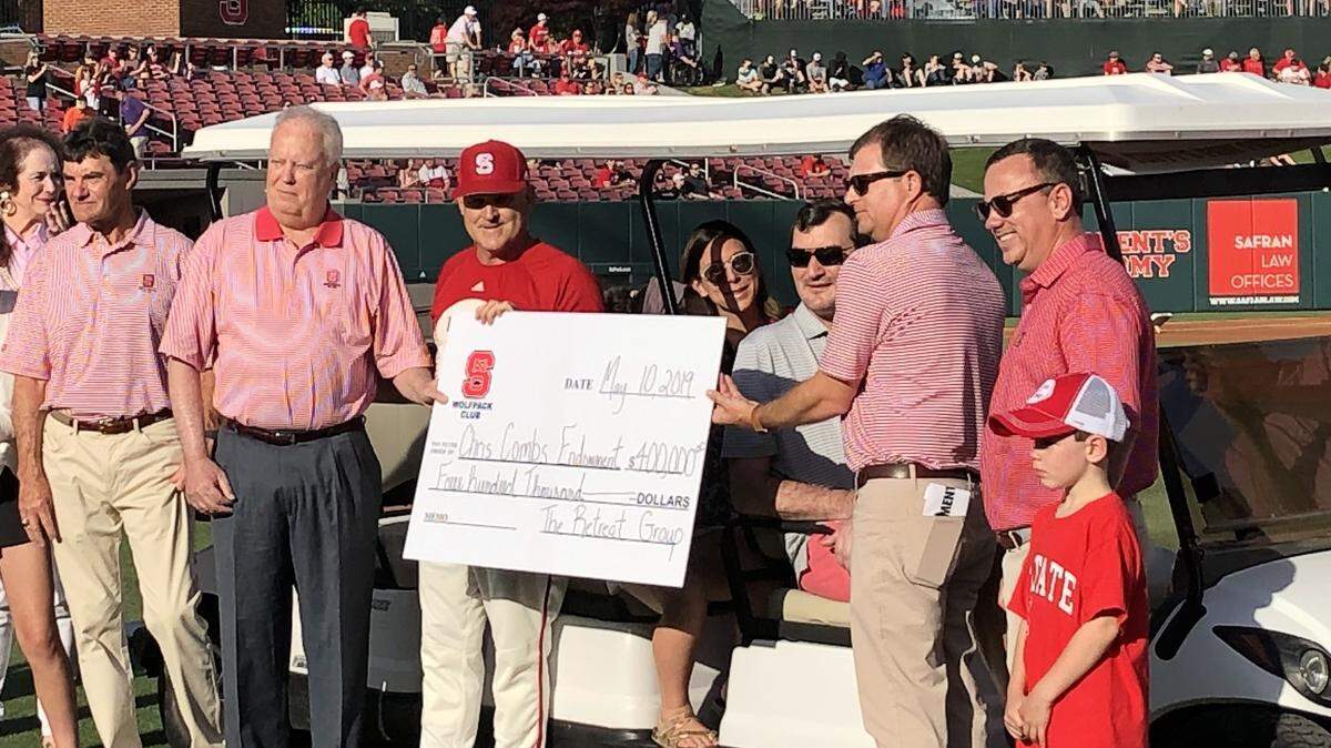 Wolfpack Club director Bobby Purcell and NC State baseball coach Elliott Avent present Chris Combs, seated in golf cart, with a $400,000 check to establish the Chris Combs baseball endowment on Friday, May 10 at Doak Field in Raleigh.