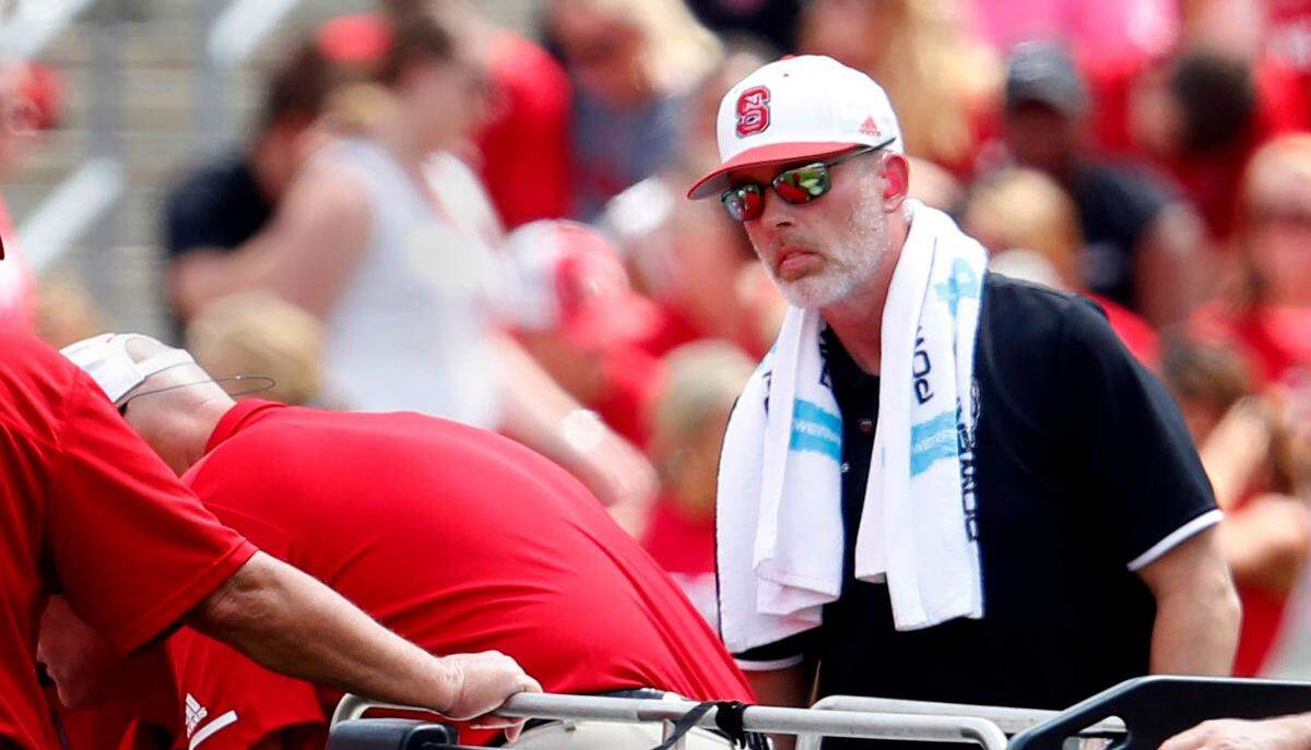 Robert M. Murphy Jr. (right), who was listed as an associate athletic director and director of sports medicine at N.C. State, helps a crew move an injured football player in the first half of N.C. State’s game against JMU at Carter-Finley Stadium in Raleigh, N.C., Saturday, Sept. 1, 2018.