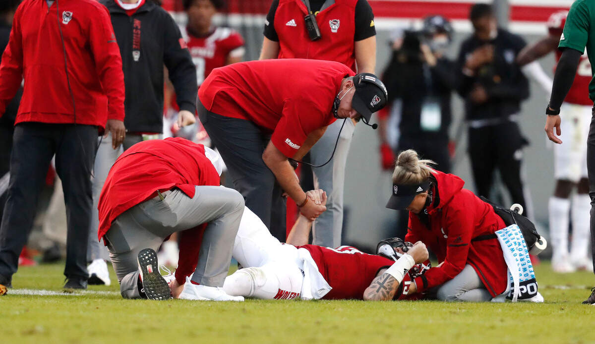 N.C. State head coach Dave Doeren holds the hand of quarterback Devin Leary (13) after he was injured during the second half of N.C. State’s 31-20 victory over Duke at Carter-Finley Stadium in Raleigh, N.C., Saturday, Oct. 17, 2020.