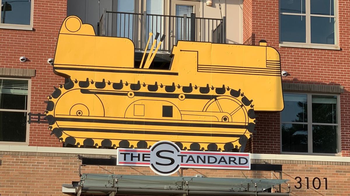 The old tractor sign from the former N.C. Equipment Co. building has a new home on The Standard student apartment building on Hillsborough Street in Raleigh.