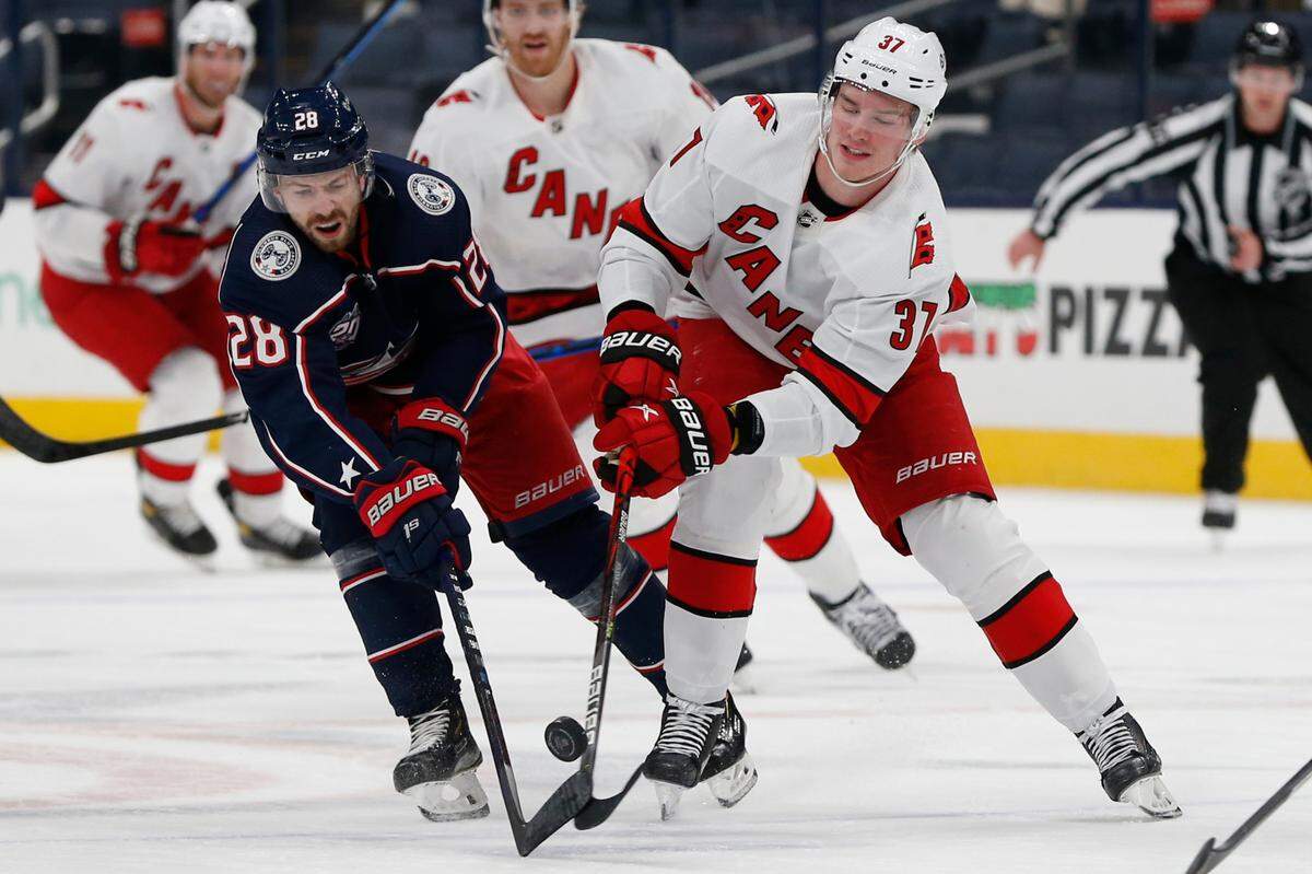 Columbus Blue Jackets’ Oliver Bjorkstrand, left, and Carolina Hurricanes’ Andrei Svechnikov reach for the puck during the first period of an NHL hockey game Thursday, March 25, 2021, in Columbus, Ohio. (AP Photo/Jay LaPrete)