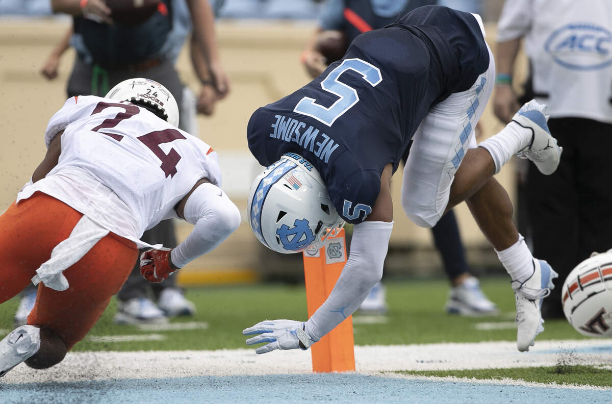 North Carolina’s Dazz Newsome (5) hurdles into the end zone for a touchdown on a six-yard carry in the second quarter against Virginia Tech ‘s Devin Taylor (24) to give the Tar Heels’ a 28-14 lead on Saturday, October 10, 2020 at Kenan Stadium in Chapel Hill, N.C.