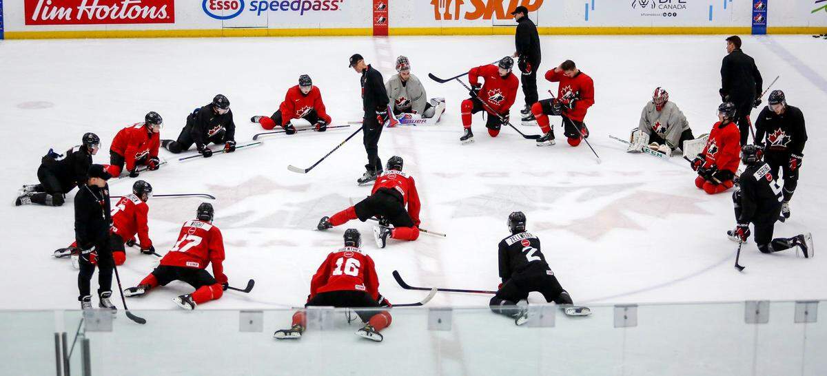 Players stretch as coach Dave Cameron, center left, gives instruction during practice at the selection camp for Canada’s junior world hockey team in Calgary, Alberta, Thursday, Dec. 9, 2021. (Jeff McIntosh/The Canadian Press via AP)