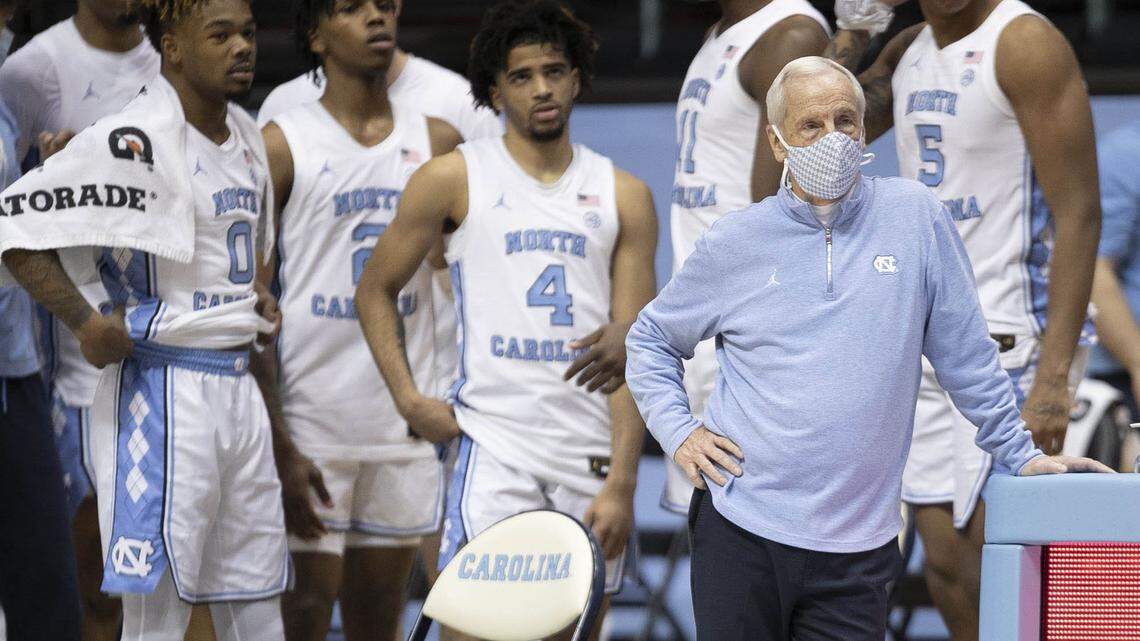 RJ Davis (4) watches from the bench in 2021 as UNC coach Roy Williams watches the reserve players run out of the clock against Duke on Saturday, March 6, 2021 at the Smith Center in Chapel Hill, N.C.