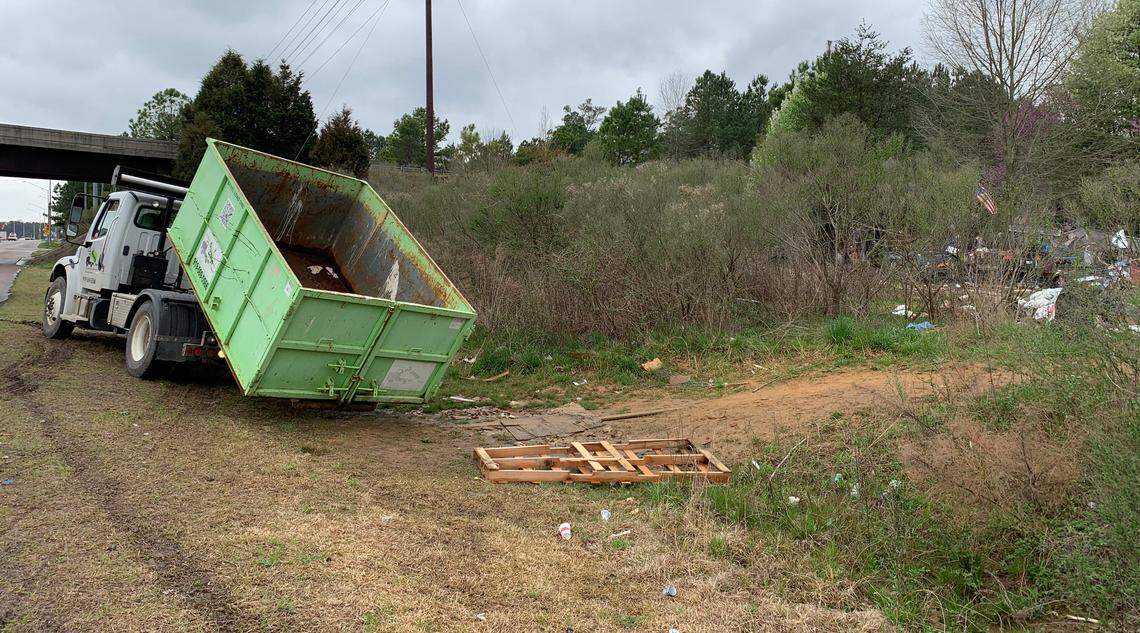 A truck from Bin There Dump That delivers a trash bin to the edge of a homeless camp off Capital Boulevard at Interstate 540 on Friday morning.