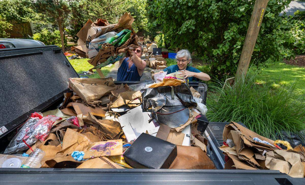 Taylor Poston and Kristie Mather load debris from a storm damaged home on Ridgefield Road on Tuesday, July 8, 2025 in Chapel Hill, N.C. The home was damaged by Tropical Storm Chantal from the flood waters of Booker Creek.