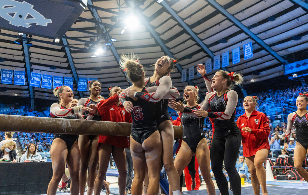 Meg Adler receives a hug from a teammate after her beam routine in N.C. State’s gymnastics meet at UNC on Jan. 19, 2024, in Chapel Hill, N.C. The Wolfpack beat the Tar Heels, 196.225-195.325.