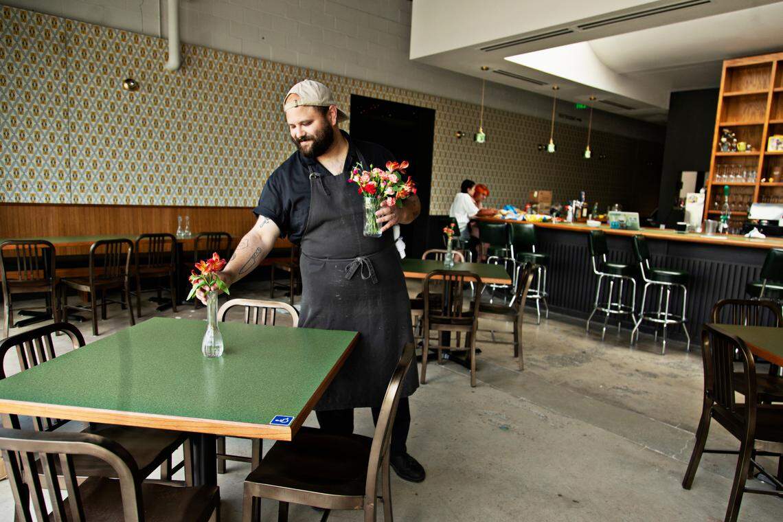 Chef Chris Lopez adds flowers to vases at Fine Folk restaurant in Raleigh on Wednesday afternoon, April 13, 2022.