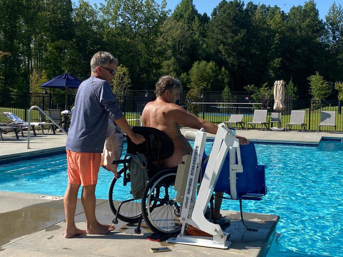 Rob Paxton assists Ed Petner on the way to the Clayton pool where they swim and Petner hopes to raise money for the Christopher Reeve Foundation.