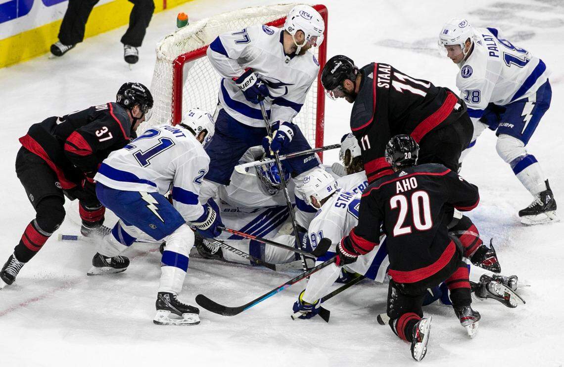 Carolina Hurricanes’ Andrei Svechnikov (37), Jordan Staal (11) and Sebastian Aho (20) frantically try to get a stick on the puck in the closing seconds of play in the third period as Tampa Bay goalie Andrei Vasilevskiy (88) secures the puck and a 2-1 victory on Tuesday, June 1, 2021 at PNC Arena in Raleigh, N.C. Vasilevskiy made 31 saves in the win.